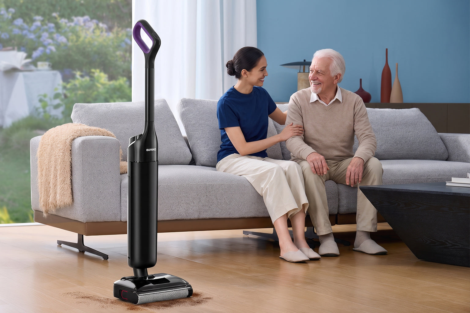 Adult visiting an elderly parent while a Eureka robot vacuum cares for the home