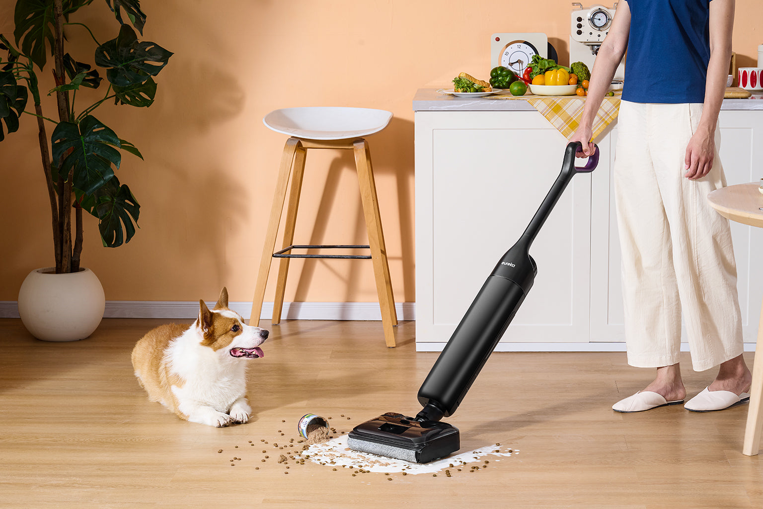 Family and a spaniel in a bright kitchen with a Eureka robot vacuum nearby